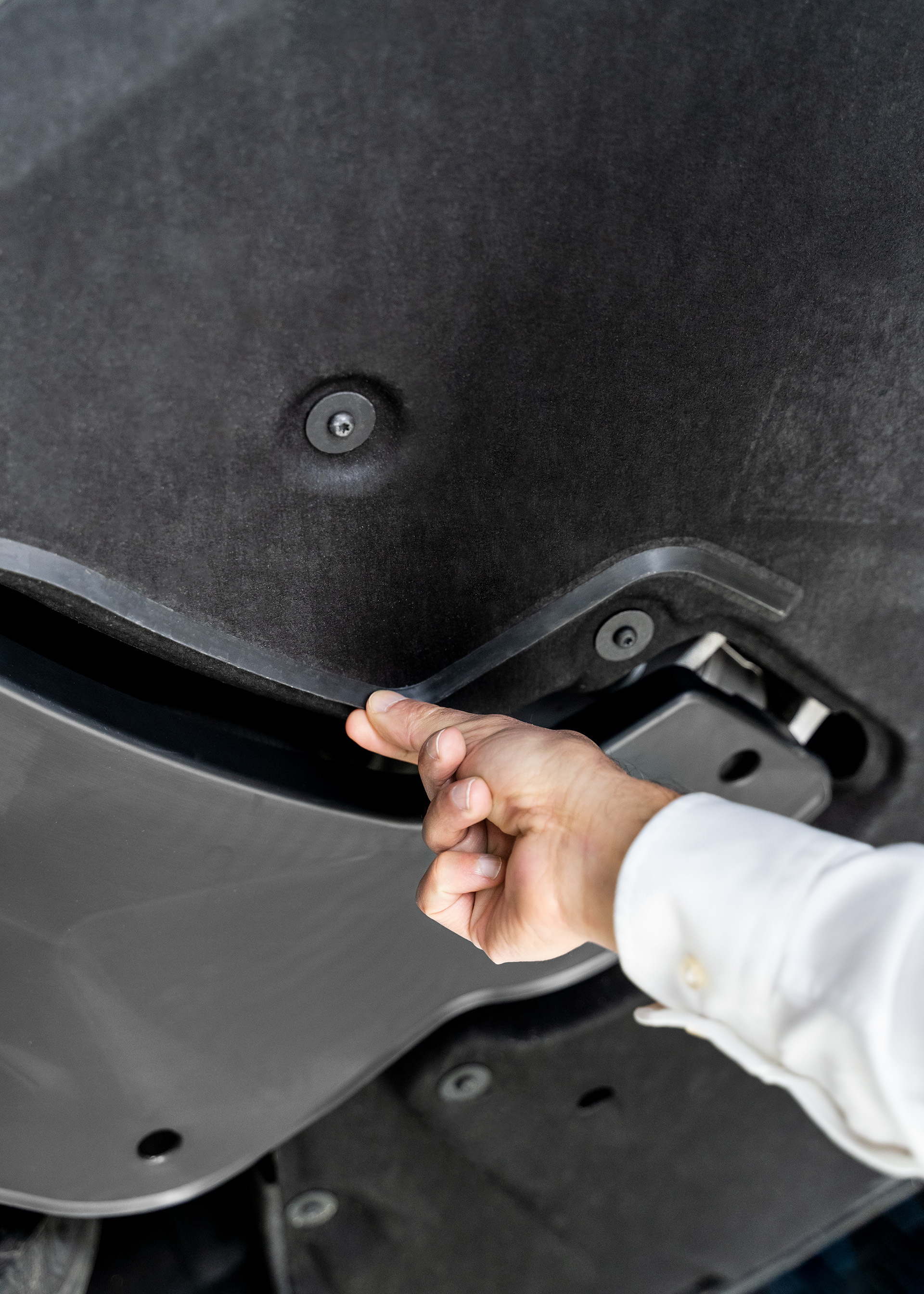 Close-up of a hand pointing out the plastic lip on the underbody of the Audi RS e-tron GT that directs airflow efficiently. 