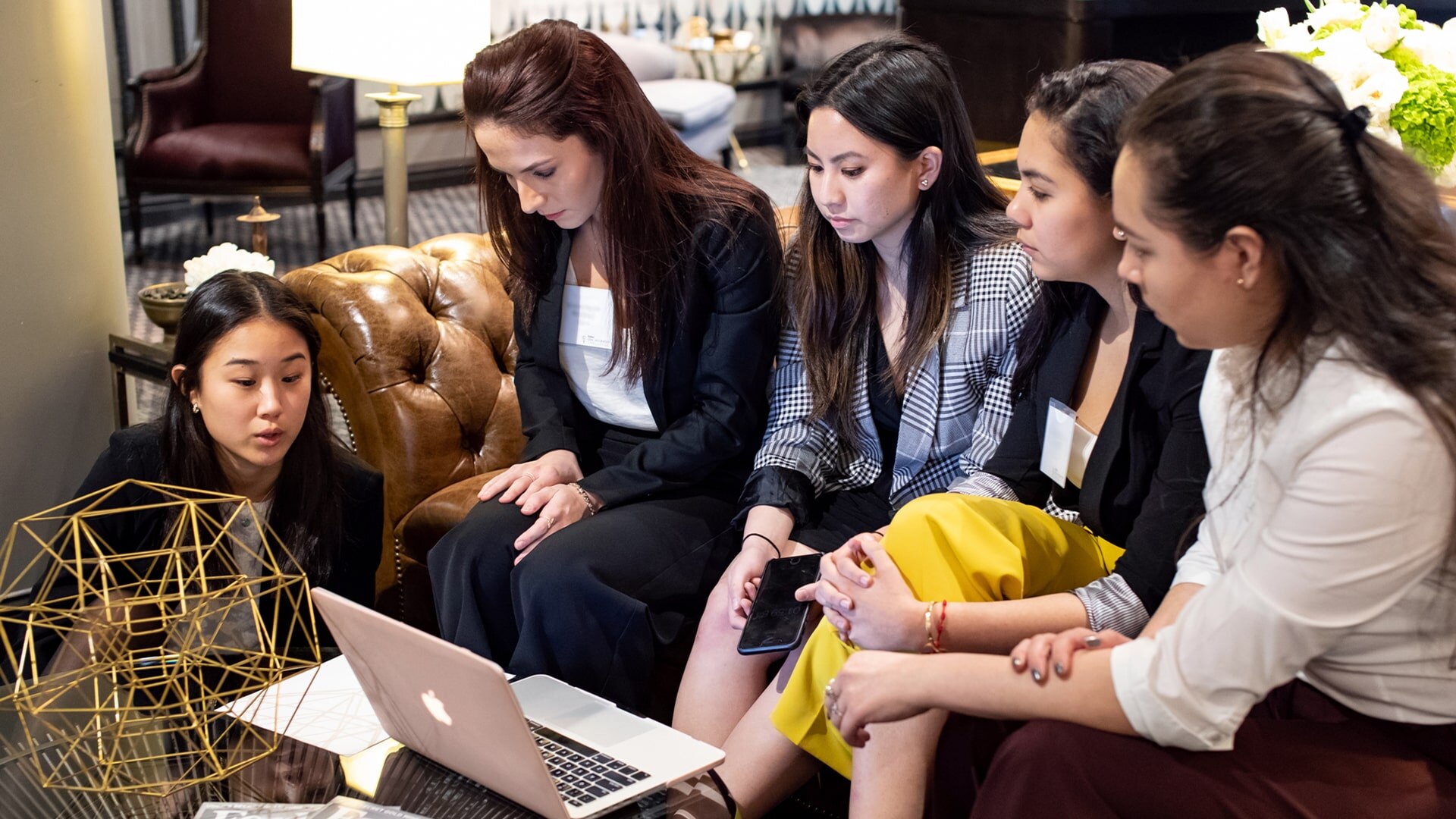 A group of women sitting around a laptop.