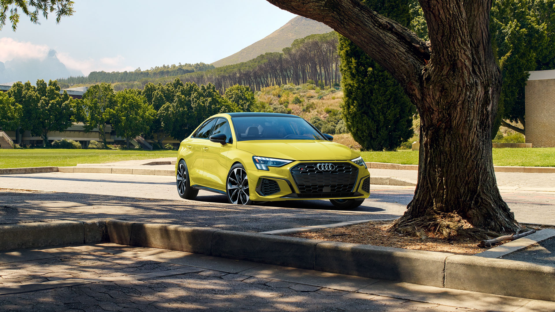 A yellow Audi S3 in a mountain parking lot. 