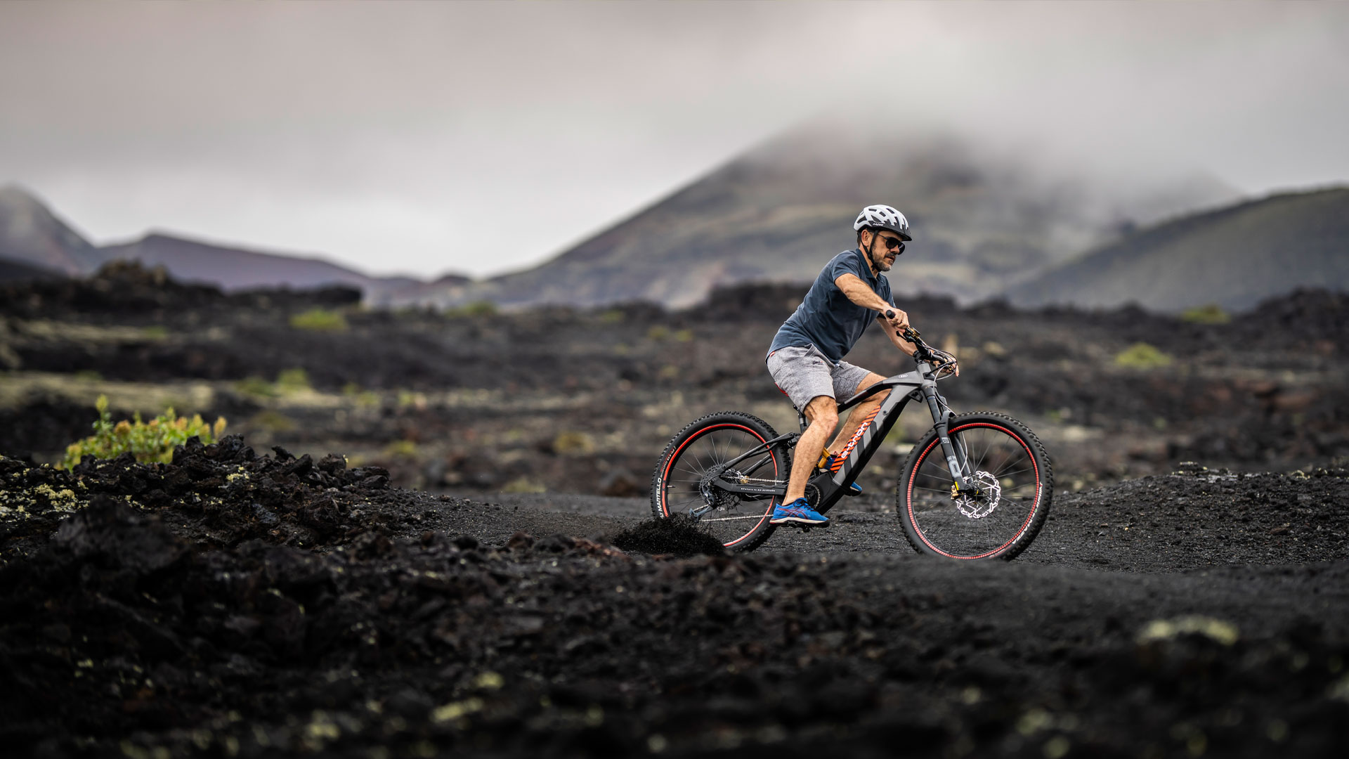 A man stopping his Audi electric mountain bike on a mud filled terrain.