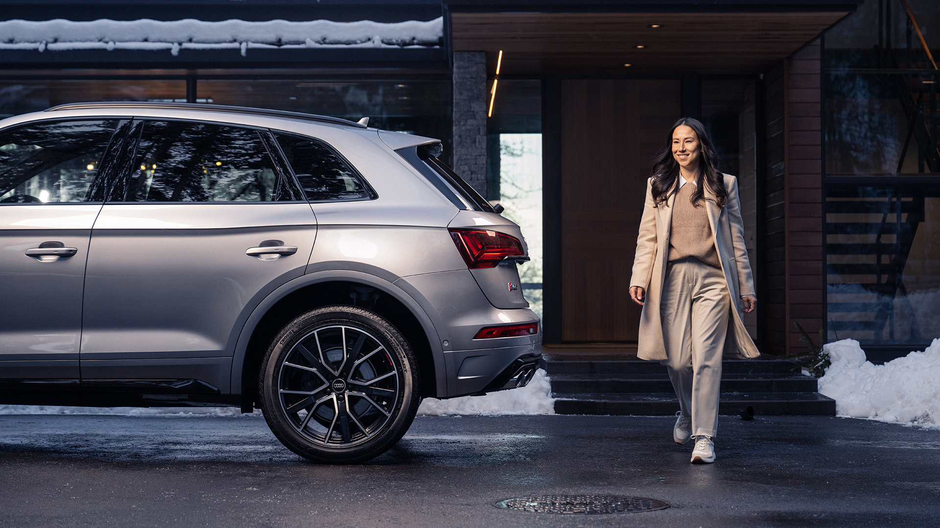 A woman standing next to a parked Audi SQ5.