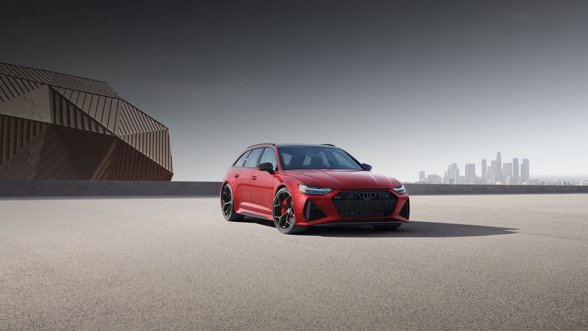 Rear view of a gray Audi RS 6 Avant driving on a coastal road. 