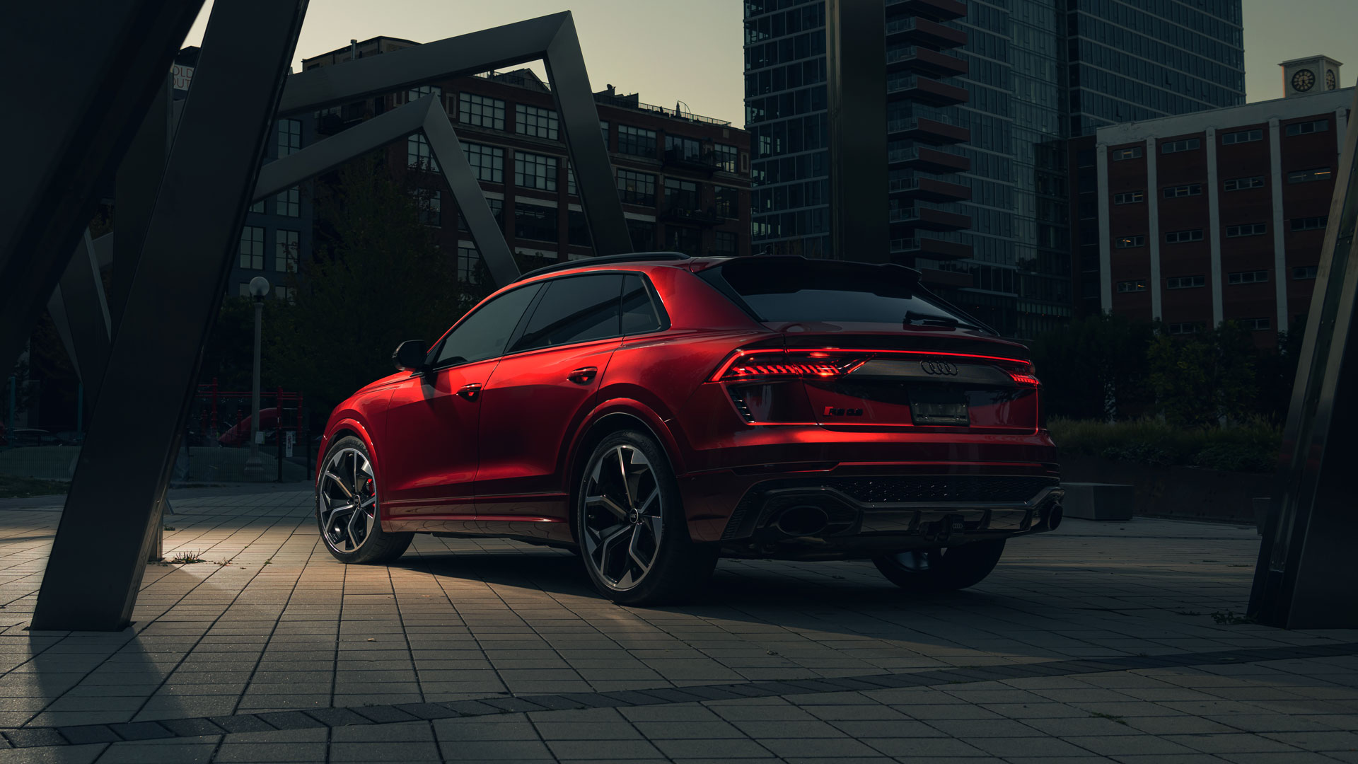 Three-quarter rear view of a red Audi RS Q8 parked on a city street.