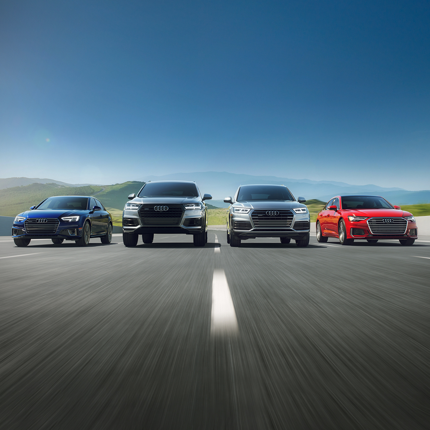 Front view of a range of Audi models in motion.